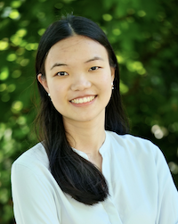 Lily has sholder length black heair and a bright smile. She wears a white blouse and small pearl earrings.