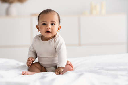 a stock photo of a baby sitting on a bed