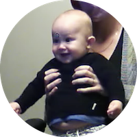 a baby participates in an eye tracking study. The baby looks at a computer screen and smiles.