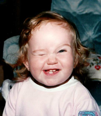 Baby Hallie winking and flashing a big cheesy grin with her first baby teeth