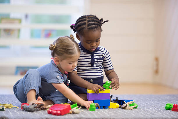 a stock photo of two toddlers playing together with legos